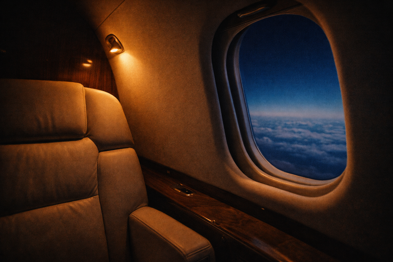 Private jet cabin — leather seat, window, clouds below